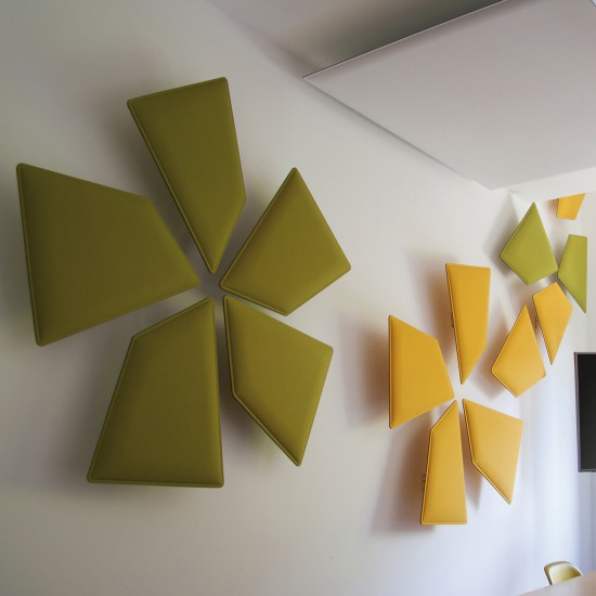 Snowsound Flap, gele en groene tweezijdige akoestische panelen in groepen gemonteerd op een witte muur
